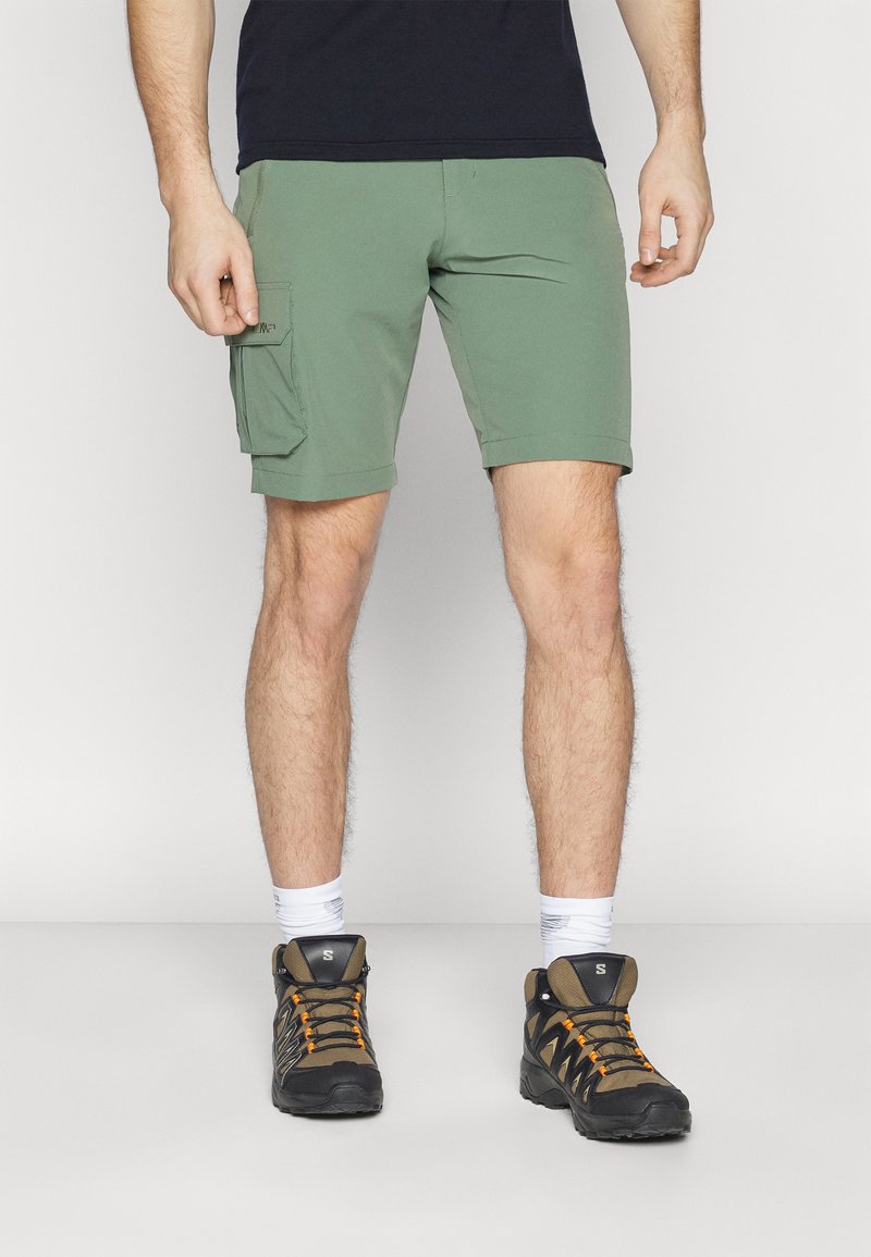 Grønne cargo shorts med sidelommer, parret med sorte og orange vandresko og hvide sokker. KASUAL og funktionelt design.