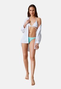 Vit skjorta med knappar, bärs över en vit bikiniöverdel med band och akvafärgade bikiniunderdelar, med släta texturer och livfulla färger.