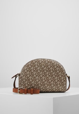 Braune DKNY Crossbody-Tasche mit Monogramm-Muster und verstellbarem Leder-Riemen, präsentiert auf einem weißen Podest vor grauem Hintergrund.
