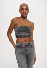 Hallid hall denimist silmuste ning "Moschino Jeans" tekstiga paljas õlgadega topp; koos kõrge vöökohaga hallide denimipükstega. Sile tekstuur.