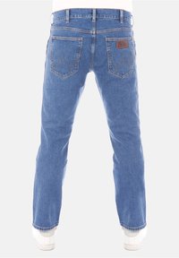 Modré džíny z denimu s rovnými nohavicemi, s hnědou koženou nášivkou na pásku a výrazným šitím na zadních kapsách.