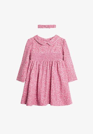 Vestido rosa de manga larga con cuerpo fruncido, patrón floral blanco, cuello redondo y diadema a juego. Tejido de algodón, falda acampanada.