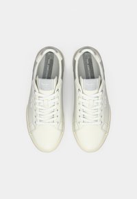 Sneakers bianchi in pelle con una finitura liscia, caratterizzati da dettagli grigi, punta rotonda e lacci piatti. Branding sulla linguetta e sul lato.