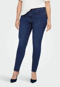 Tmavě modré skinny džíny vyrobené z denimu, s středním pasem, pětistranným designem a slim fit střihem. Vypadají skvěle s černými vysokými podpatky.