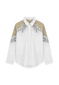 Camisa blanca de manga larga con botones, que presenta paneles de hombro beige y patrones decorativos negros a lo largo del canesú y las mangas.