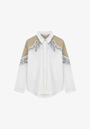 Witte lange mouwen overhemd met knopen, voorzien van beige schouderpanelen en zwarte decoratieve patronen langs de schouders en mouwen.
