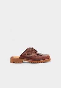 Zapatos de cuero marrón tipo mocasín con suela de goma, que cuentan con detalles de cordones y costuras.