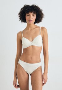 Hvit bralette med blondekant og tynne stropper, matchende hipstertruser, glatt stoff og delikate detaljer langs kantene.