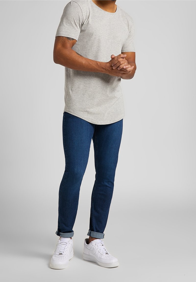 Light gray short-sleeve t-shirt paired with dark blue slim-fit jeans, rolled cuffs, and white sneakers, featuring a smooth texture and classic design.