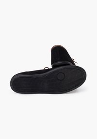 Zapatos de ante negro con una suela de goma negra texturizada, acentos marrones en la parte trasera y cordones marrones. La suela presenta un diseño de banda de rodadura con patrón.