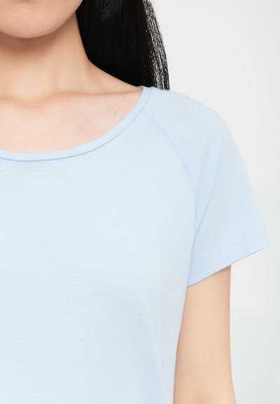 Light blue short-sleeve t-shirt with a round neckline and a soft texture. Features raglan sleeves and subtle stitching details.