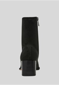 Stivaletto nero alla caviglia con tomaia in tessuto elegante, tacco a blocco e cerniera laterale per una facile indossabilità. Texture liscia e dettagli di design minimal.