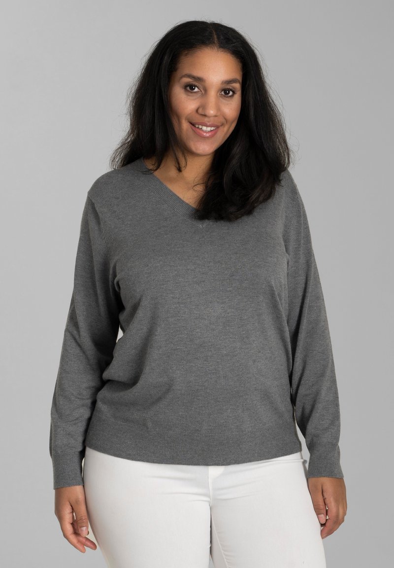 Pulover gri cu decolteu în V și mâneci lungi, fabricat dintr-un material moale. Purtați peste pantaloni albi cu talie ajustată. Design minimalist, fără modele.