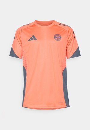 Orange sports T-shirt med grå accenter, med korte ærmer, en rund halsudskæring og et logo af FC Bayern München på fronten.