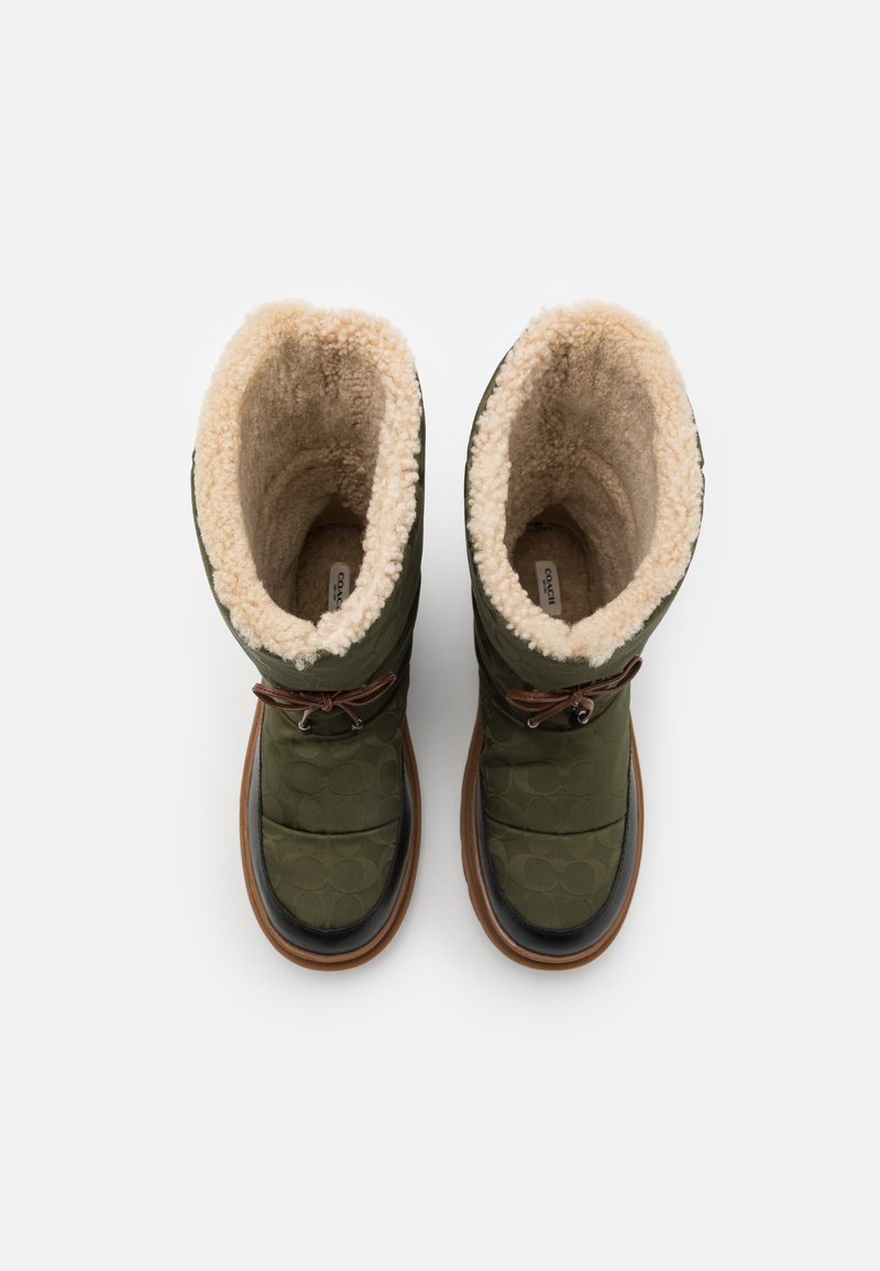 Zielone pikowane botki z futrzanym wykończeniem, zaokrąglone czubki, brązowe skórzane akcenty i gumowa podeszwa. Zapięcie w stylu sznurowanym z oczkami.