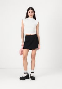 Valge ilma varrukateta lühike topp, must rätik, must platvormkingad ja roosa käekott. Minimalistlik disain, puhaste joonte ja kontrastsete värvidega.