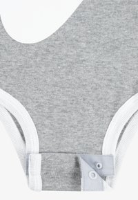 Grå bomulls bodysuit med vit elastisk trim, tryckknappar i botten och en stor, vit grafisk design på framsidan.