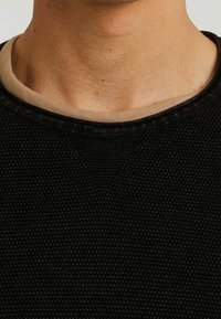 Czarny sweter o strukturze z dekoltem w kształcie zaokrąglenia i beżowym wykończeniem, wykonany z dzianiny o subtelnych wzorach.