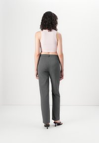Grå skreddersydde bukser med rett snitt, glatt tekstur og en diskret baklomme, parret med en kort rosa tank-top.