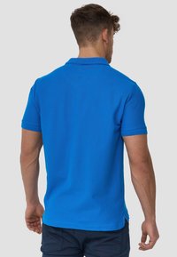Polo-shirt bleu à manches courtes avec un col classique et des poignets côtelés. Présente des fentes latérales et un tissu texturé pour le confort.