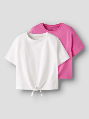 T-shirts en coton à manches courtes blancs avec nœud à l'avant et rose uni, tous deux à col rond, présentés sur fond gris.