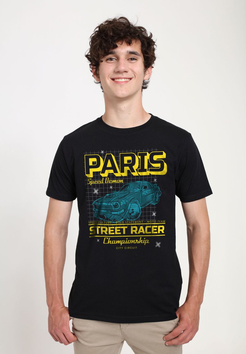 Černé bavlněné tričko s grafickým designem, na kterém je napsáno "PARIS" žlutou barvou a ilustrací modrého auta. Významné detaily zahrnují textové prvky a mřížkované pozadí.