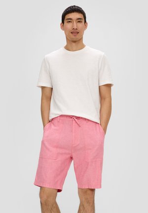 Shorts en lin rose avec taille à cordon de serrage, deux poches avant et tissu texturé. Associé à un t-shirt blanc uni à col rond.