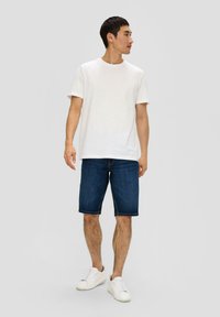 T-shirt en coton blanc, shorts en denim bleu et baskets blanches. Tenue décontractée avec un design simple et une coupe standard. Pas de motifs visibles.