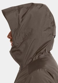 Ruskea vedenpitävä takki hupulla, sileällä pinnalla ja sivuprofiilinäkymällä, jossa on vetoketjutettu yksityiskohta kaula-alueella.