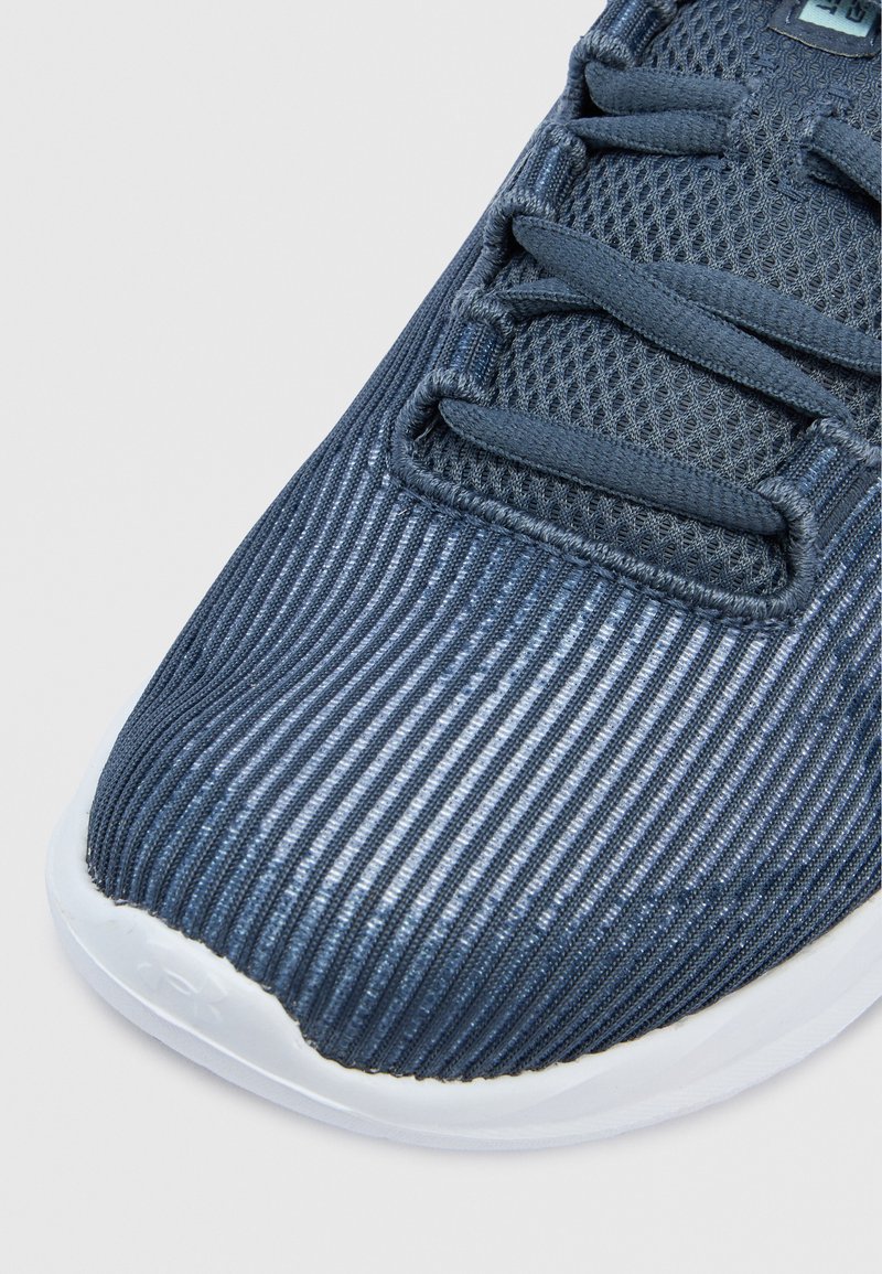 Zapatilla deportiva azul con parte superior texturizada a rayas, que presenta un diseño de malla y suela de goma blanca. Cordones integrados en el empeine para un ajuste seguro.