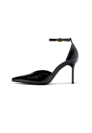 Čierna lodička s vysokým podpätkom a špicatou špičkou, s remienkom okolo členka a zlatou prackou, lesklý kožený povrch, ihličkový podpätok na bielom pozadí.