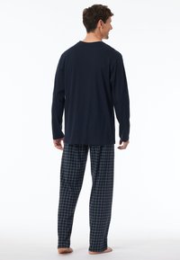 Top de manga larga marino y pantalones de pijama a cuadros en azul oscuro con patrón de cuadrícula gris claro. Material de algodón suave, ajuste relajado.