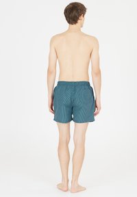 Mandens badshorts i mørk teal med lodrette hvide striber. Har en elastisk talje og sidelommer. Glat stofstruktur.
