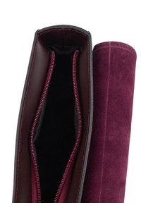 Burgunder-samtige Tasche mit schwarzen Akzenten, die einen offenen Reißverschluss zeigt, der ein schwarzes Innenfutter und burgunderfarbene Fütterung offenbart und die Detailverarbeitung der Nähte präsentiert.