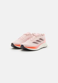 Scarpe da corsa rosa chiaro con tomaia in rete traspirante, che presenta accenti rosa scuro e una suola ammortizzata. Design minimalista, con una delicata pattern.