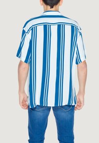Camicia a maniche corte di colore azzurro chiaro e bianco con strisce verticali. Presenta un colletto classico e una vestibilità rilassata. Tessuto morbido.