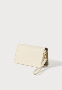 Cream leather wallet with a textured finish, folding design, gold hardware, and a detachable wrist strap. Branding embossed on front.