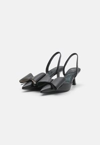 Black leather slingback heels with pointed toes, featuring oversized bow detail on the front and a low, tapered heel. Textured insole.