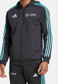 Svart zip-up hoodie med turkosa tre-rands detaljer, med en logotyp på bröstet och slät tyg. Inkluderar en huva och framfickor.