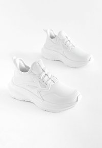 Weiße Sport-Schuhe verfügen über ein strukturiertes Mesh-Obermaterial, eine gepolsterte Sohle und ein schlankes Design mit einer Ziehlasche. Minimalistisch und vielseitig für verschiedene Aktivitäten.