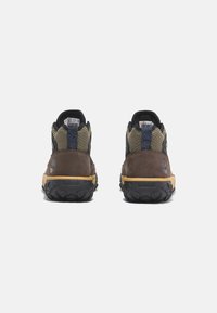 Scarpe da escursionismo marroni e nere realizzate in suede, rete e gomma; presentano un tallone con motivo e una suola resistente per una buona aderenza.