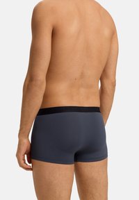 Boxers ajustados para hombre en tejido gris oscuro. Material suave y elástico con una cinturilla negra de goma con el logo de la marca. Diseño ceñido.