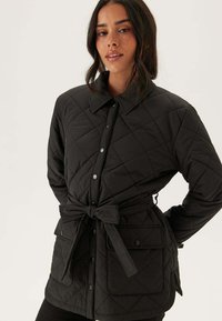 Černá prešívaná bunda s klasickým límcem, předními knoflíky, páskem v pase a dvěma bočními kapsami s hladkou texturou.