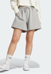 Ljusgrå shorts med ribbad textur, dragsko i midjan och sidofickor, matchade med vita strumpor och skor med svarta detaljer.