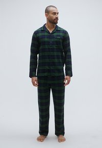 Zelena i mornarsko plava pidžama na kockice izrađena od mekanog tkanina; s gornjim dijelom dugih rukava s gumbima i pripadajućim hlačama opuštenog kroja.
