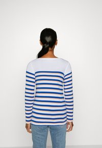 Długosleeve top z niebieskimi, pomarańczowymi i białymi poziomymi paskami. Gładki materiał, okrągły dekolt i dopasowane mankiety.