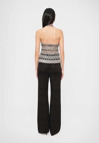 Nyakba akasztható topp, bézs és fekete színű texturált mintával, légiesen omló, fekete cikk-cakkmintás nadrággal párosítva.