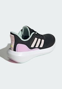 Scarpa sportiva nera con tomaia texturizzata, dettagli rosa, fodera verde menta chiaro e una suola intermedia bianca. Presenta tre strisce sul lato.