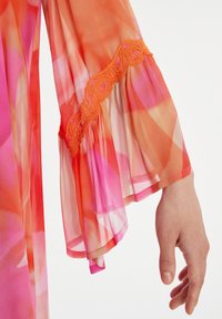 Lange, fließende Ärmel aus durchscheinendem, leichtem Stoff mit einem Verlauf von Orange- und Rosatönen. Verziert mit filigranen, orangenen Spitzenapplikationen.