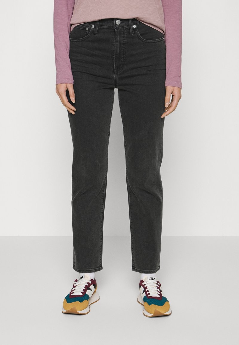 Černé džínové kalhoty s přímým střihem nohavic, s pěti kapsami a klasickým zapínáním na knoflíky. Nošeny s barevnými teniskami a dlouhým rukávem trička.